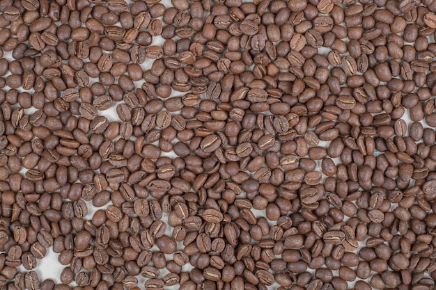 Bunch of coffee beans on beige surface