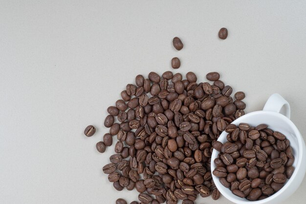 白いマグカップからのコーヒー豆の束