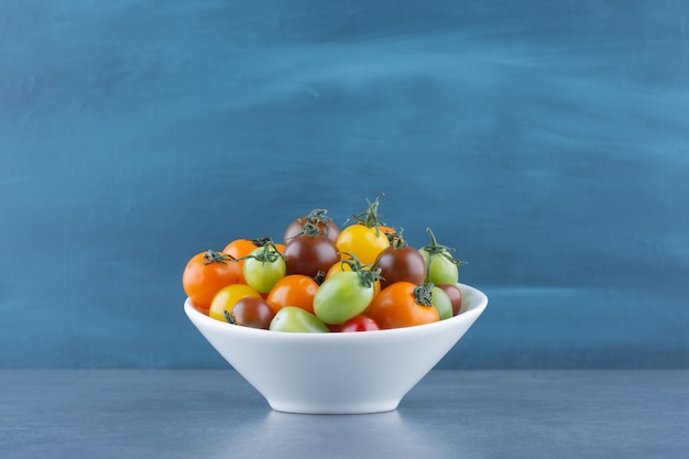 Bunch of colorful tomatoes in white bowl.