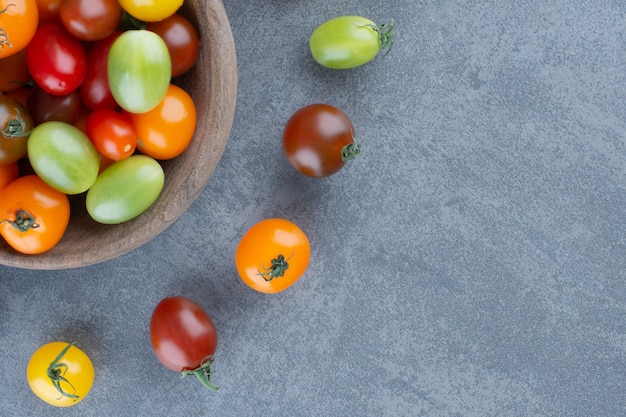 Bunch of colorful tomatoes in wooden bowl.