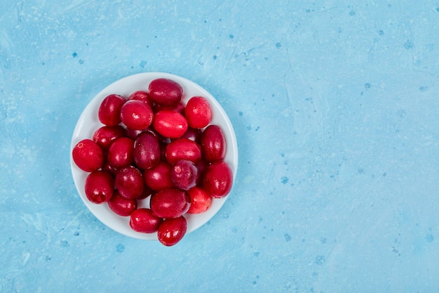 Free photo bunch of cornel berries on white plate. top view.