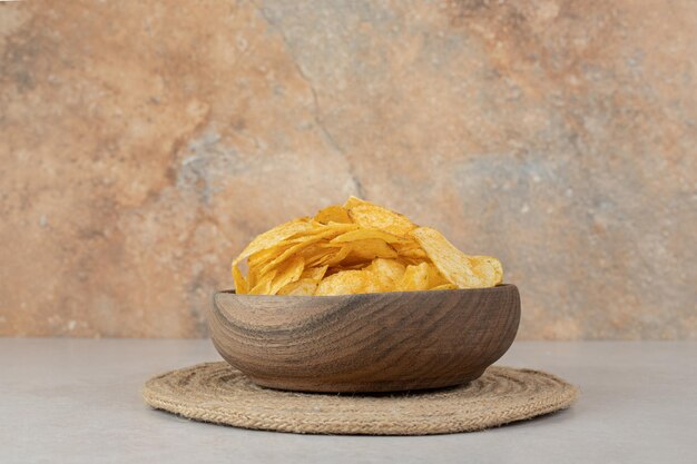 Bunch of crispy chips in wooden bowl