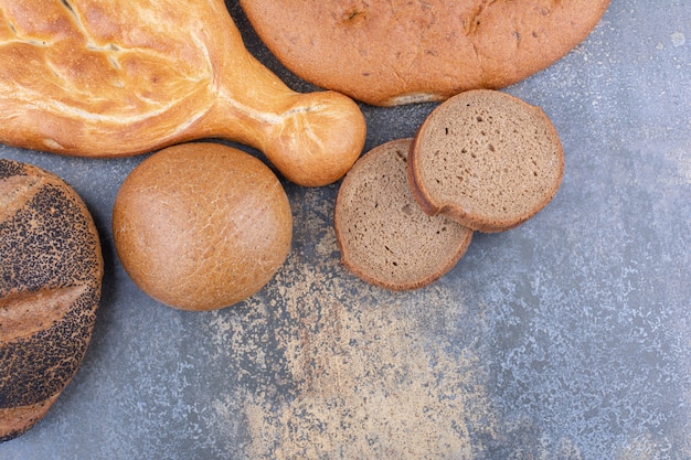 Bunch of different bread types bundle together on marble surface