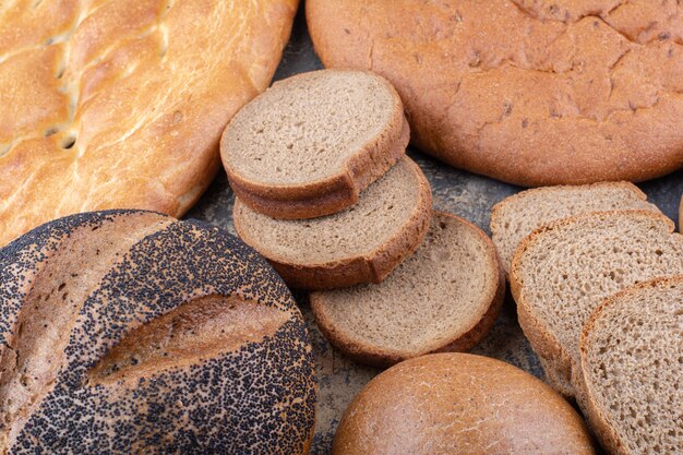 Bunch of different bread types bundle together on marble surface