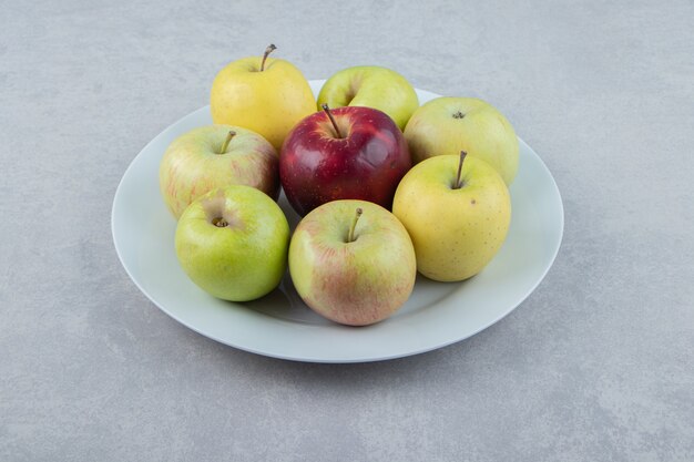 Bunch of fresh apples on white plate