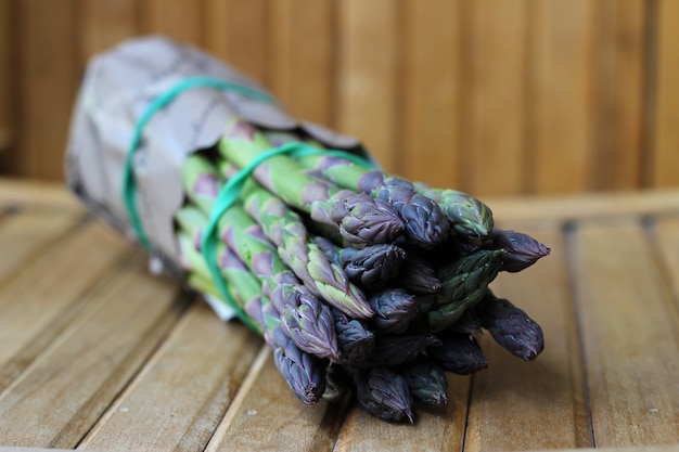 Free photo bunch of fresh asparagus on wooden table