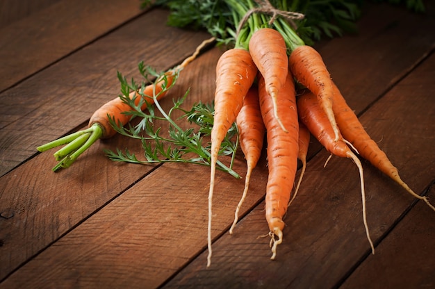 Bunch of fresh carrots with green leaves over wooden table