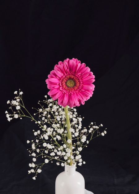 Букет из свежих цветочных веточек и розового цветка в бутылке
