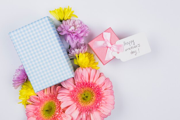 Bunch of fresh flowers near tag with words and present boxes