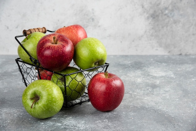 Mazzo di mele fresche verdi e rosse poste in un cestino di metallo.