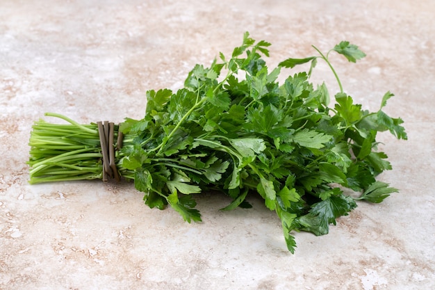 A bunch of fresh parsley, on the marble table. 