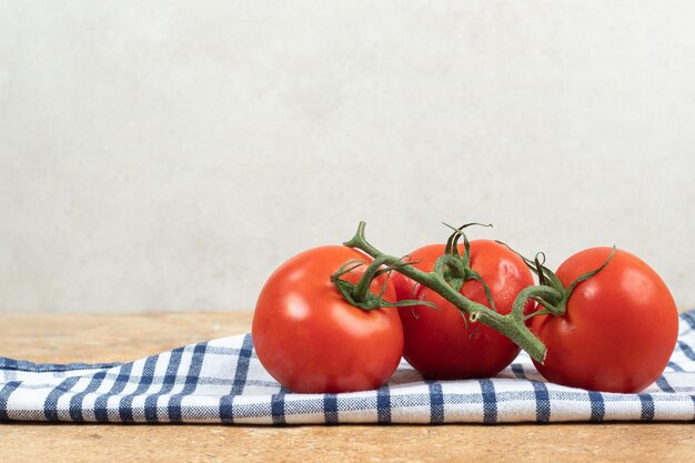 식탁보에 녹색 줄기를 가진 신선한 빨간 토마토의 무리