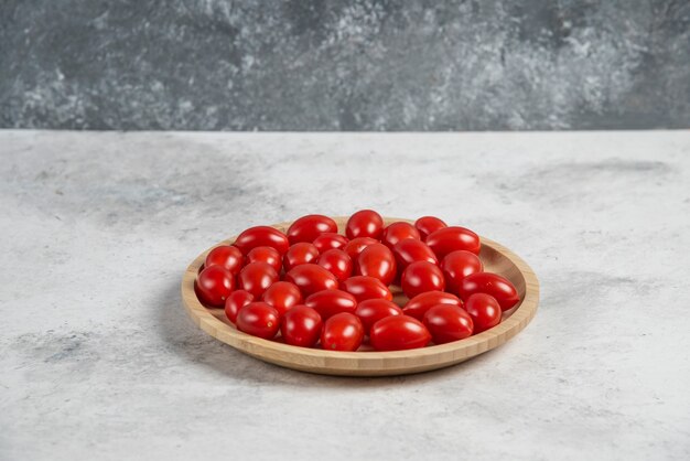 나무 접시에 신선한 토마토의 무리입니다.