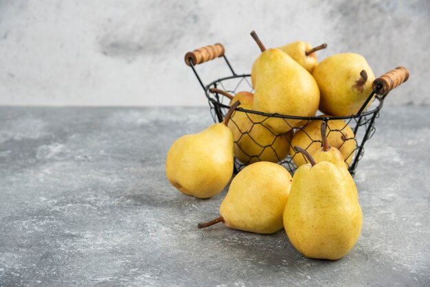 大理石の表面の金属製のバケツに新鮮な黄色の梨の束。