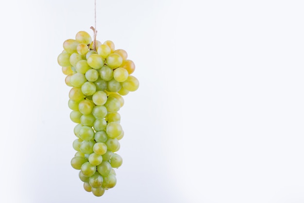 A bunch of grape hanged on the white surface