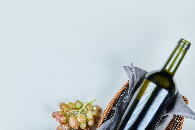 Free photo bunch of grapes and a bottle of wine on gray background. high quality photo