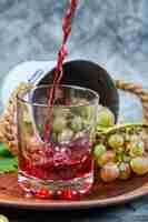 Foto gratuita grappolo d'uva e un bicchiere di succo su marmo.