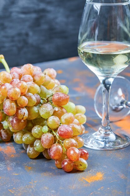 Bunch of grapes and a glass of wine on blue background. High quality photo