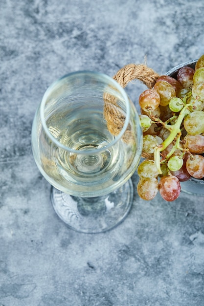 Foto gratuita grappolo d'uva e un bicchiere di vino sull'azzurro.