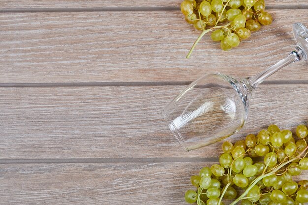 A bunch of grapes and wine glass on wooden surface
