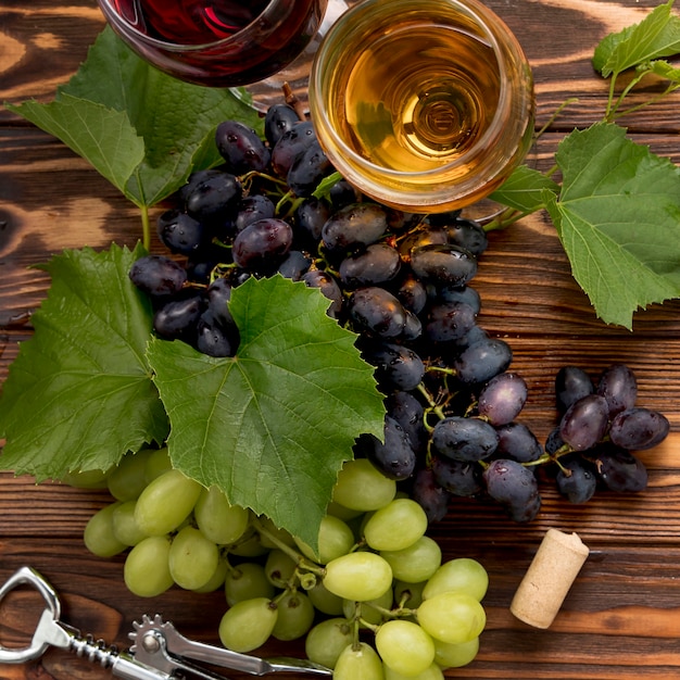 Bunch of grapes with corkscrew on wooden background