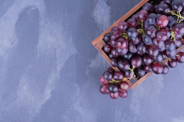 A bunch of grapes in a wooden tray.