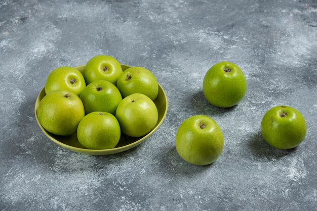 Bunch of green apples in green bowl.