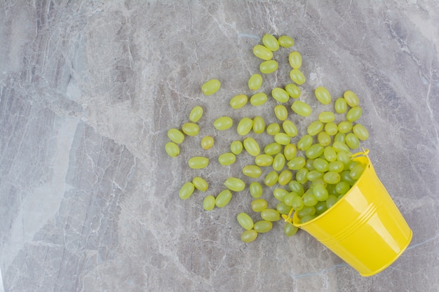 Bunch of green grapes out of bucket on stone surface. 