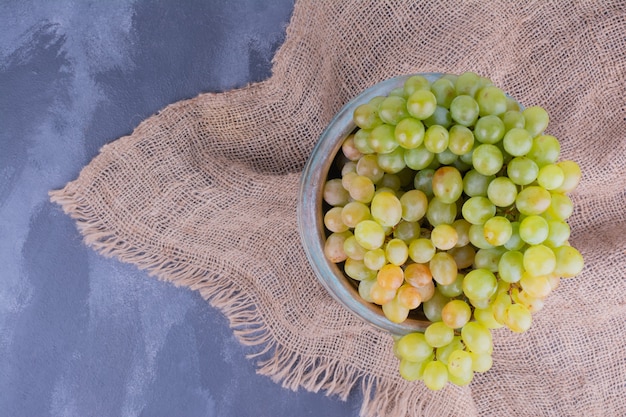 Bunch of green grapes in the platter on blue.