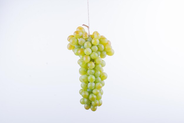 A bunch of green grapes on white table.