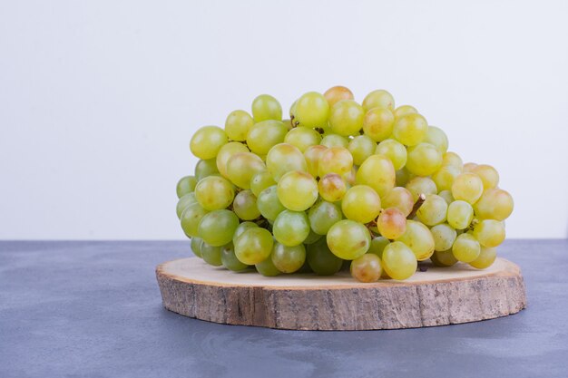 Bunch of green grapes on wooden board.