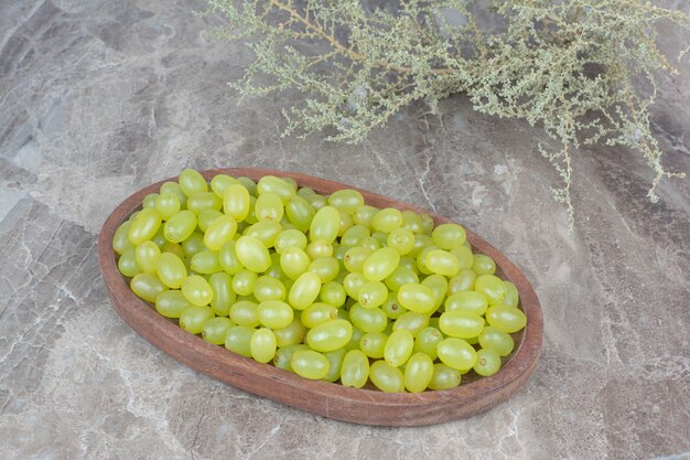 Bunch of green grapes in wooden bowl. 