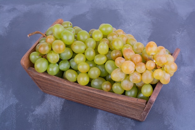 Bunch of green grapes in a wooden tray.