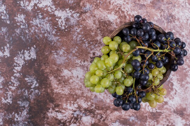 A bunch of green and red grapes in the middle on the marble