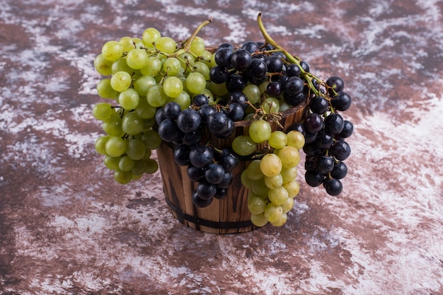 A bunch of green and red grapes in a wooden bucket