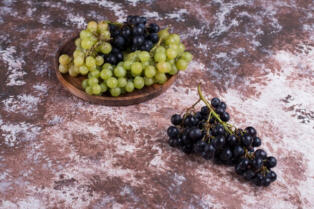 A bunch of green and red grapes in a wooden platter