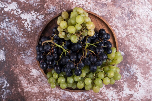 A bunch of green and red grapes in a wooden platter