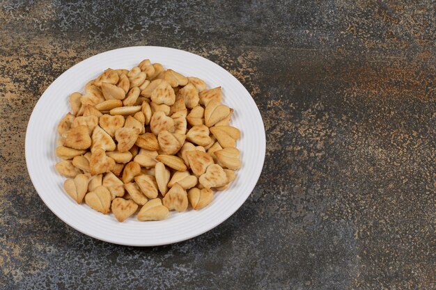 Bunch of heart shaped crackers on white plate.