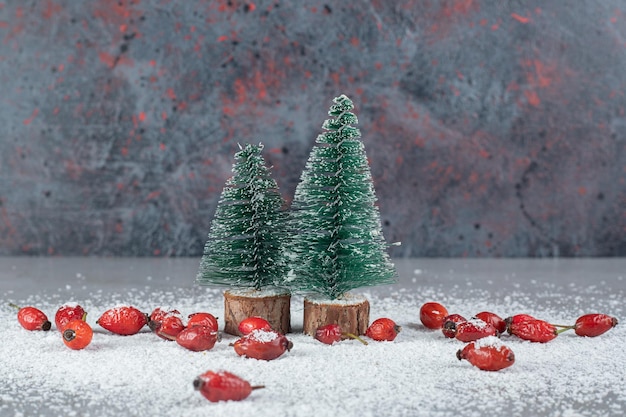 Bunch of hips, coconut powder and christmas tree figurines on marble table.