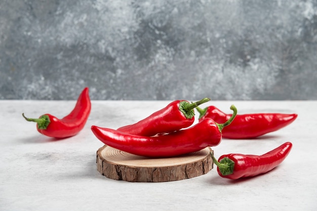 Bunch of hot chili peppers on wood piece.