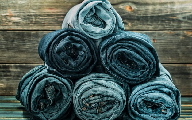 Free photo bunch of jeans twisted on a wooden wall, fashionable clothes