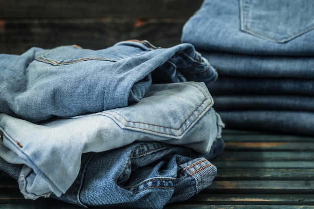 bunch of jeans on wooden background, fashionable clothes