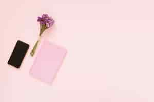 Free photo bunch of lavender flowers; cellphone and diary on pink backdrop