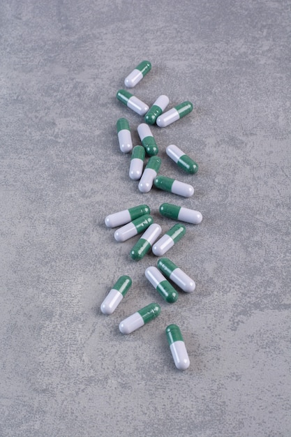 Bunch of medical capsules on marble table.