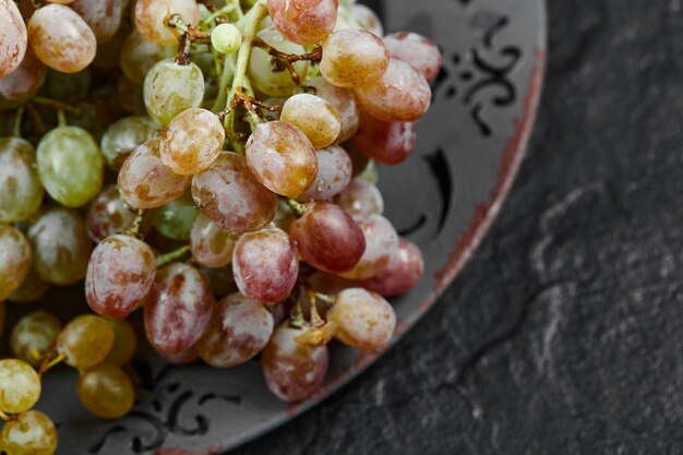 A bunch of mixed grapes on a ceramic plate, close up. High quality photo