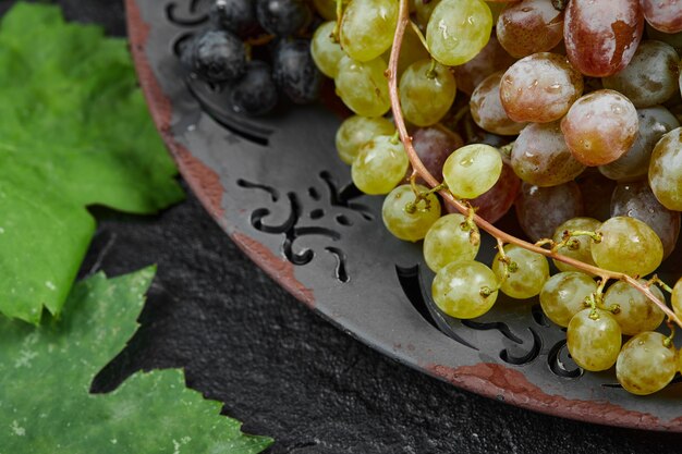 A bunch of mixed grapes on a ceramic plate. High quality photo