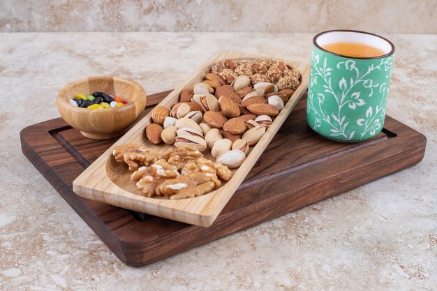 Bunch of nut kernels on wooden plate with hot tea