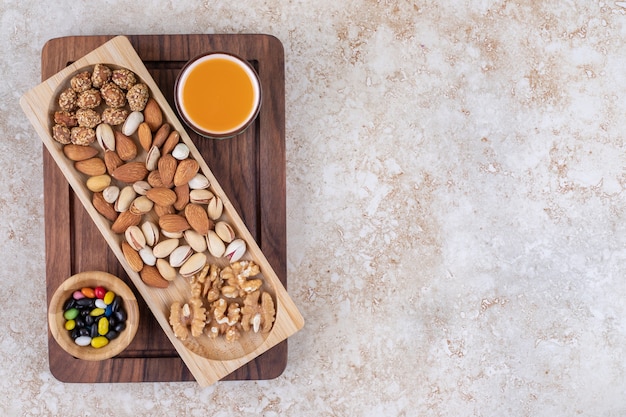 Free photo bunch of nut kernels on wooden plate with hot tea