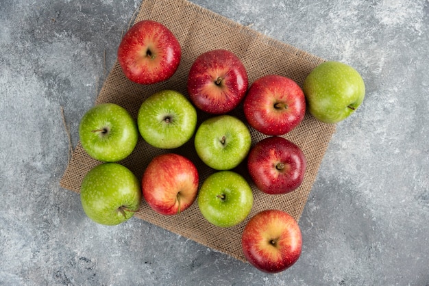 Бесплатное фото Связка свежих зеленых и красных яблок на мешковине.