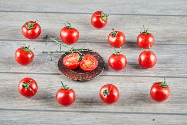 무료 사진 신선한 육즙 토마토의 무리와 나무 테이블에 토마토 조각.